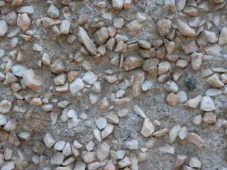 Light stones in concrete for the background. Uneven edges of small rubble.