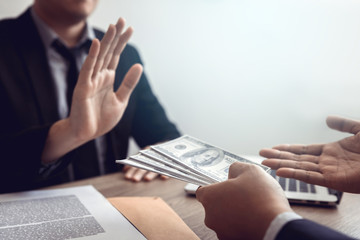 Businessperson refusing bribe given money by partner with anti bribery corruption concept.