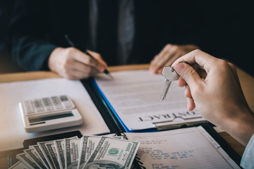 Salesman house brokers provide key to new homeowners in office.