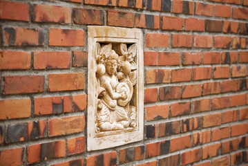 old red brick wall with built-in traditional Thai statue design