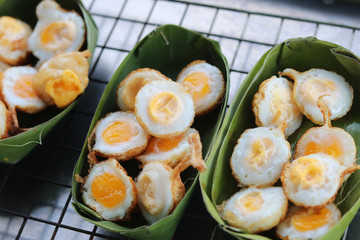 Fried quail eggs (Khanom Krok Khai Nok Krata in Thai language) in Thai style recipe on banana leaf plates.  This snack is among the most popular in street food of Bangkok,Thailand.