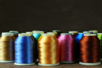 Bobbin with colorful threads on a dark background, close-up.