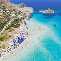 Stunning aerial view of the Spiaggia Della Pelosa (Pelosa Beach) full of colored beach umbrellas and people sunbathing and swimming in a beautiful turquoise clear water. Stintino, Sardinia, Italy.