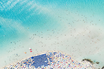 Prachtig luchtfoto van de Spiaggia Della Pelosa (Pelosa Beach) vol gekleurde parasols en mensen die zonnebaden en zwemmen in een prachtig turquoise helder water. Stintino, Sardinië, Italië.