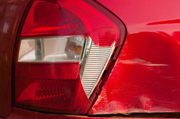 tail light car. broken rear brake light. red passenger car. dent and scratch on the rear fender....