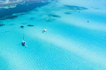 View from above, stunning aerial view of some boats sailing on a beautiful turquoise clear water. Spiaggia La Pelosa (Pelosa beach) Stintino, Sardinia, Italy.