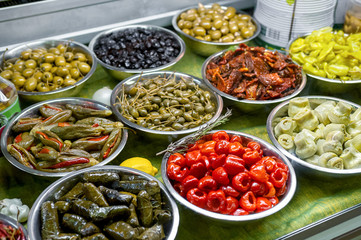 salad bar with cold snacks marinated olives, peppers and mushrooms in metal bowls