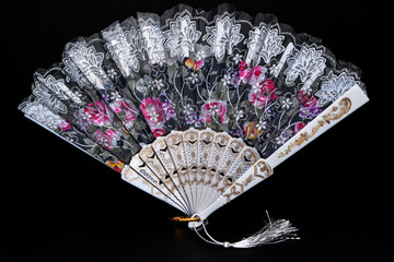 Flamenco hand fan with colorful pattern isolated on black background