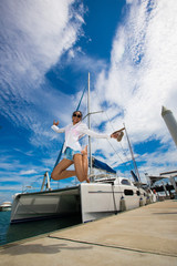 Beautiful Mix Race Tanned skin Woman high jump along Luxury Yachts in Marina Bay Club, white shirt...