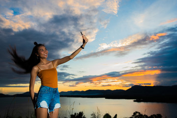 Open World Sky with wind Cloud over sunset red ray beam to adult asian woman long black hair skinny vast who feel lonely happy success to stand on top of clip ocean sight view, copy space low exposure