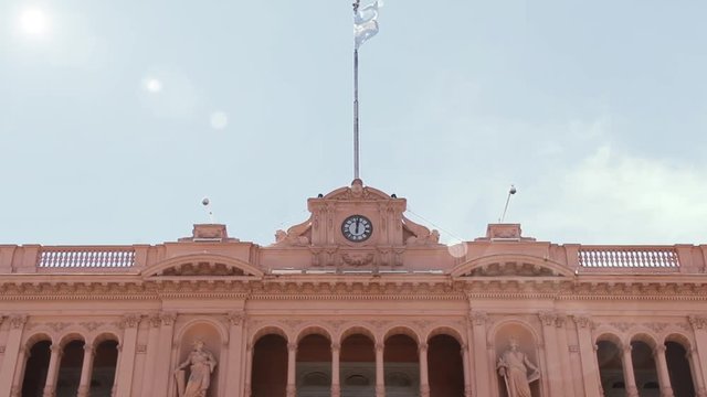  The Casa Rosada and Argentina Flag Over Blue Sky, in Buenos Aires, Argentina.  Slow Motion Shot. 