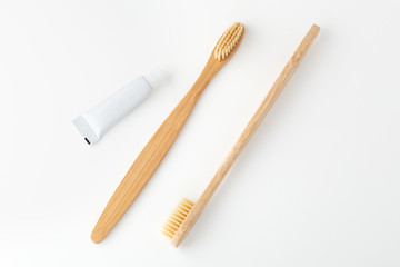 Wooden toothbrushes and toothpaste on white