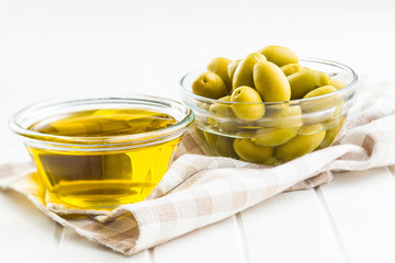 Green olives and olive oil in glass bowl.