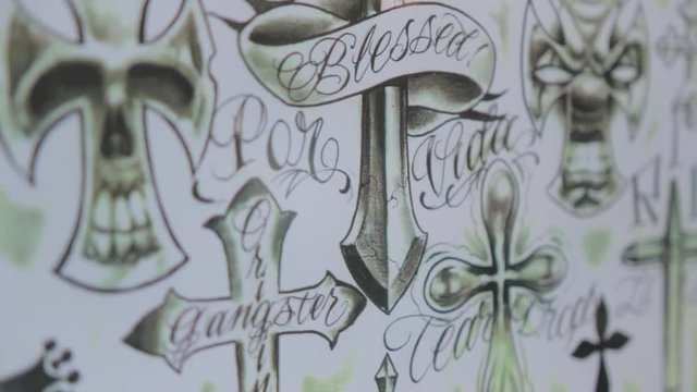 Footage of hand drawn cross tattoo designs at a tattoo shop.