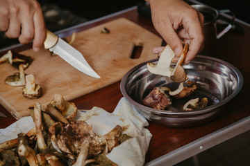 Hand pouring sliced mushrooms in bowl