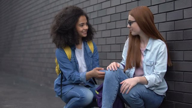 Kind afro-american teenager helping sad female classmate, new school adjustment