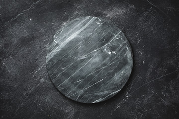 Round serving tray made of marble on a dark background. The view from the top. Copy space
