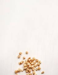 Caramelized popcorn on a white wooden background. Caramel popcorn isolated on white back. Golden caramel popcorn closeup. Snacks and food for a movie.
