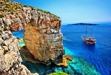 Tourist boat passing next to Trypitos (also known as "Kamara"), a natural rocky arch at Paxos island, Ionian Sea, GREECE. In the background, Antipaxos island.