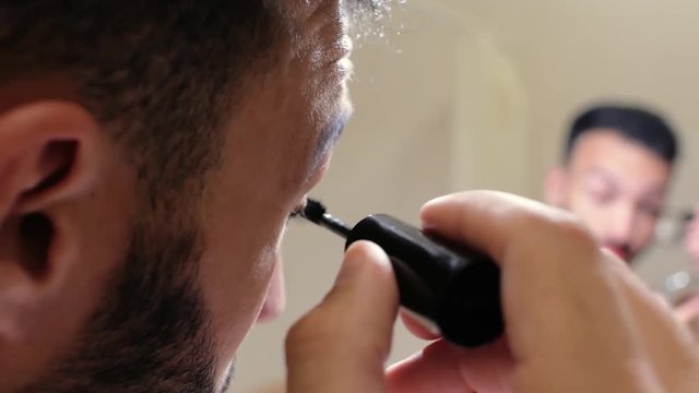 a man with a beard paints eyelashes with mascara. Pretty man applying makeup.4k. 4k video