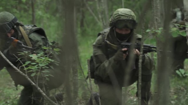 Patrol soldiers in camouflage with assault rifle walking through the forest, enemy spotted, military action in the woods, special forces group.