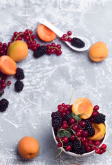 The explosion of different berries. Photo, red currant, black currant, blackberry, apricot on a concrete background.
