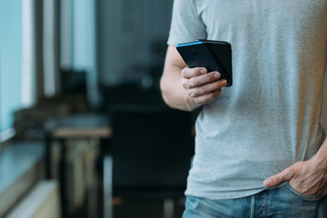 Information technology in corporate life. Cropped shot of man holding two smartphones. Blur office background. Copy space.