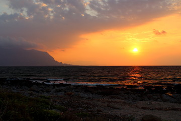 evocative immagine of sunset over the sea with promontory in the background