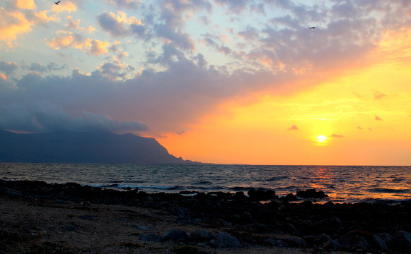 evocative immagine of sunset over the sea with promontory in the background