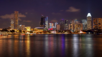 Fototapeta na wymiar Skyline panorama of Singapore Downtown at night with Esplande and business buildings with offices. Views from Marina Bay.