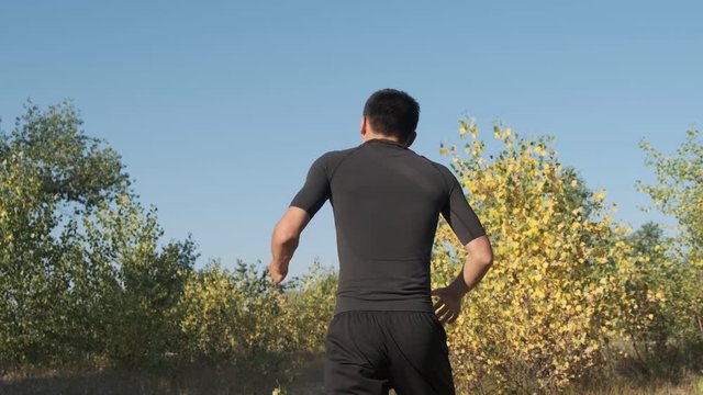 A young sportsman boxer and kickback training in the park. The young guy works out the technique of kicks