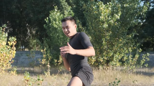 A young sportsman boxer and kickback training in the park. The young guy works out the technique of kicks