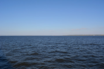 Landscape with blue sky and dark blue water of Volga river.