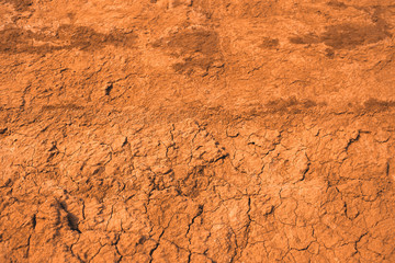 The surface of the cracked dried clay background. Brown and cracked soil background. Clay. Ocher.