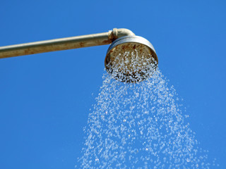 Close up outdoor shower head with water drops on blue sky background