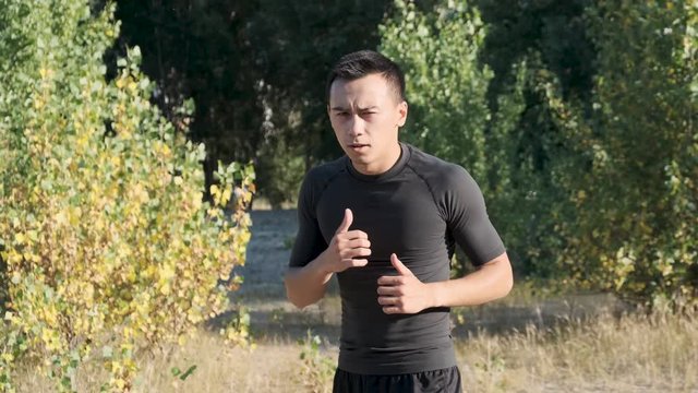 A young sportsman boxer and kickback training in the park. The young guy works out the technique of kicks