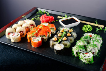 Sushi and sushi roll set on black stone table.