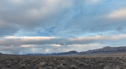 Storm clouds above mountains with cars traveling in the distance