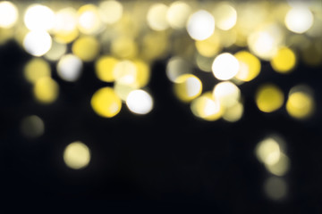 Shining golden bokeh fall from top to bottom on black background. Holiday concept