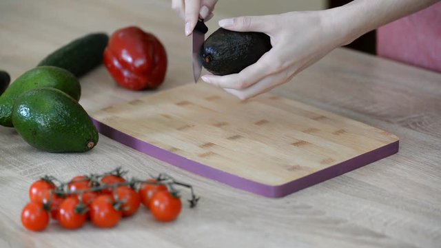 Slicing fresh avocado on a wood cutting board.