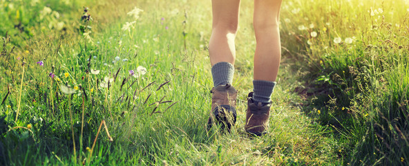 Young woman hiker walking on trail in grassland