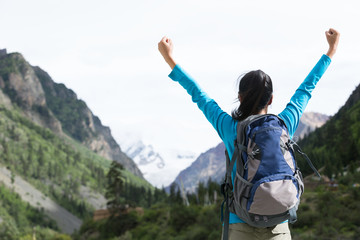 Cheering Hiker with outstretched arms standing in front of snow mountain