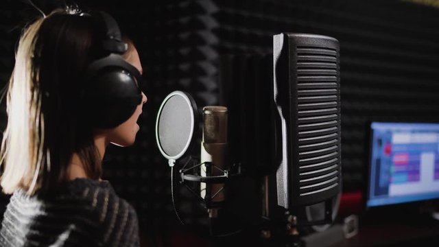 Singer child is training to make music in professional studio. Song production process. Talented kids. Track recording
