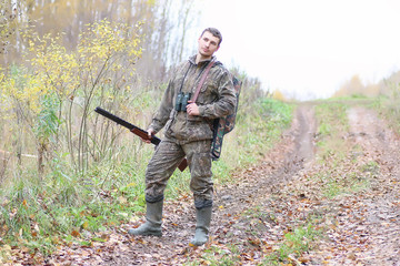 Man in camouflage and with guns in a forest belt on a spring hunt