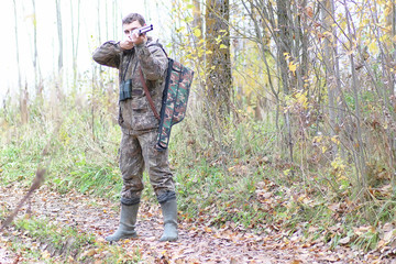 Fototapeta premium Man in camouflage and with guns in a forest belt on a spring hunt