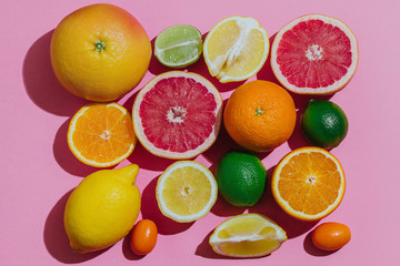 Citrus fruits fresh cutted on a pastel pink background grouped top view