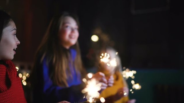 Children have fun with sparklers, kids dancing at Christmas background. Happy new year. Slow motion