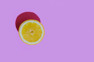Fresh cutted lemon on a pastel violet background closeup at the left side of the table