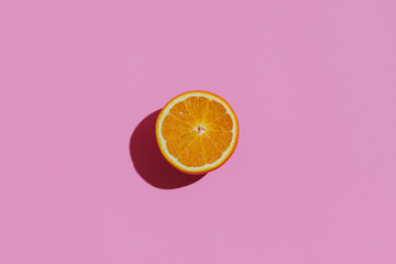 Fresh cutted orange on a pastel pink background at the center of the rectangular table