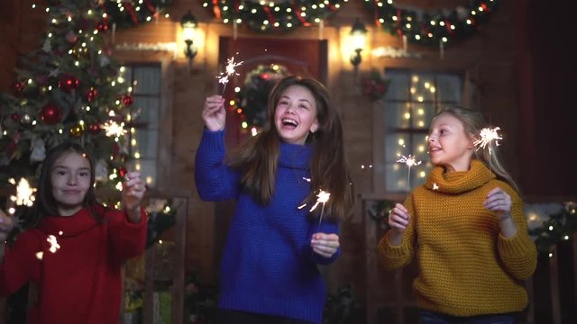 Children have fun with sparklers, kids dancing at Christmas background. Happy new year. Slow motion